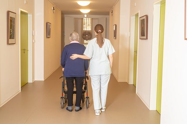 Pflegerin begleitet einen Gast über den Flur des Hospizes